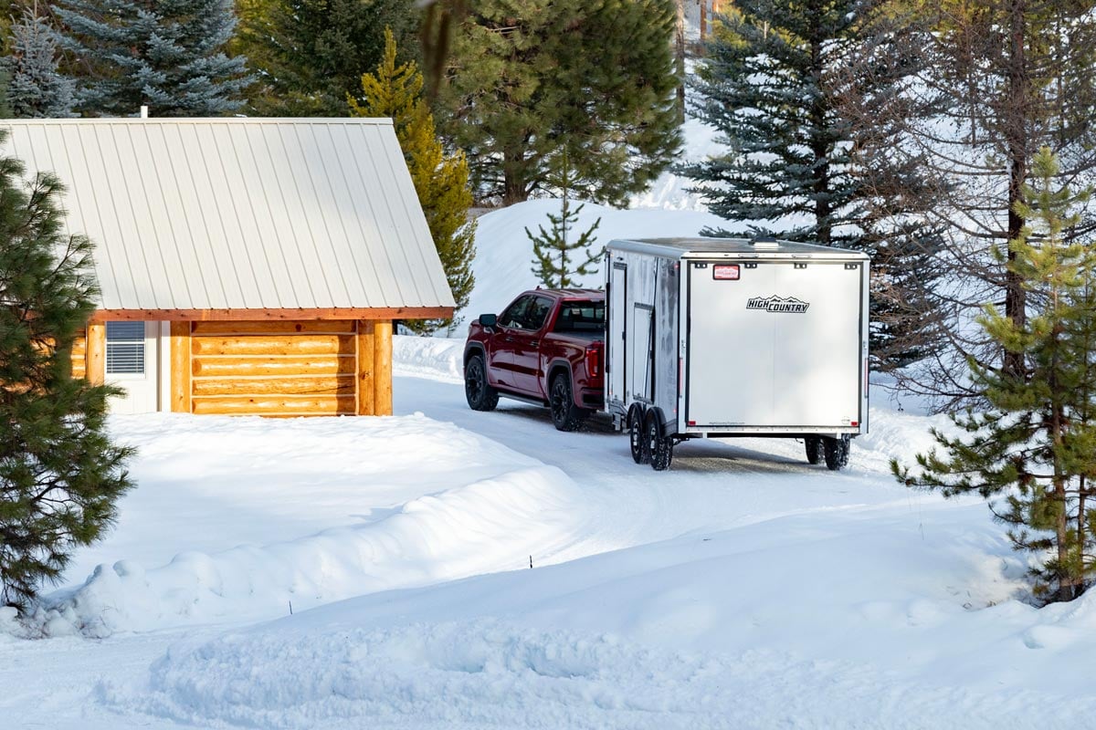 High Country Enclosed All Sport Elevation Snow White Trailer With Red Truck In Front Of Cabin